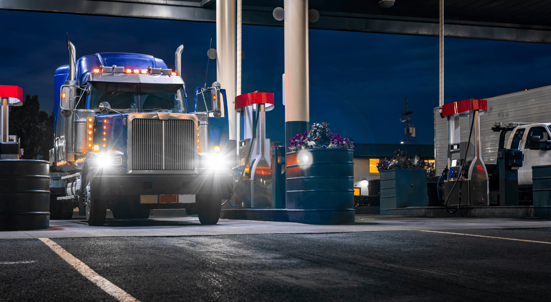 A transport truck refueling at night at an automated fuel station terminal