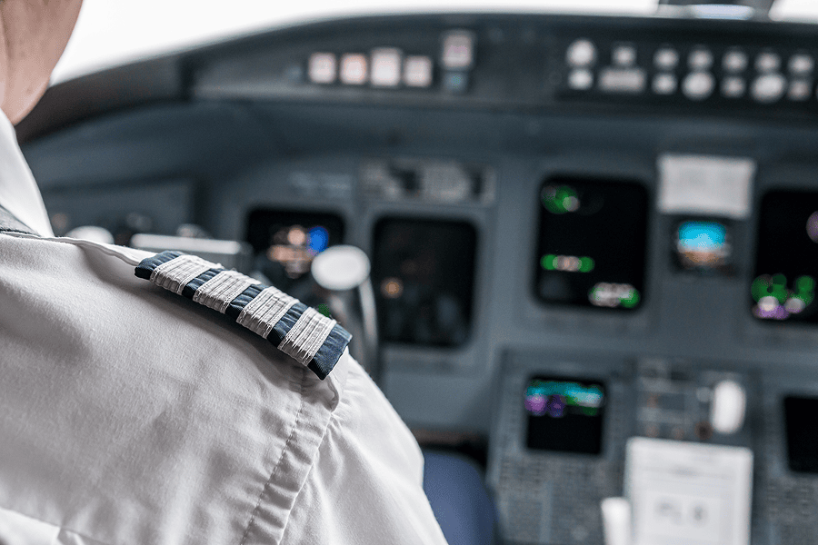 Pilot in cockpit with epaulettes visible.