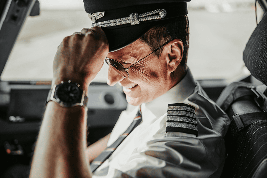 Pilot smiling in cockpit, wearing uniform.