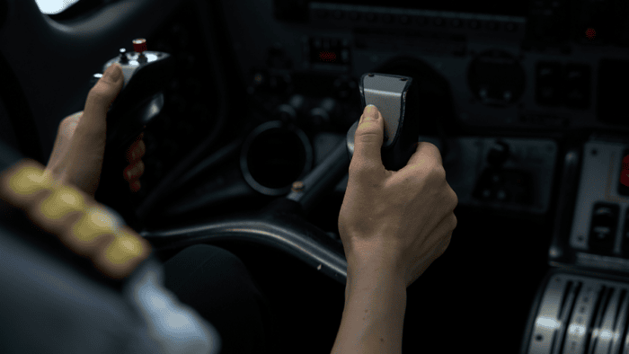 Pilot's hands on cockpit controls.