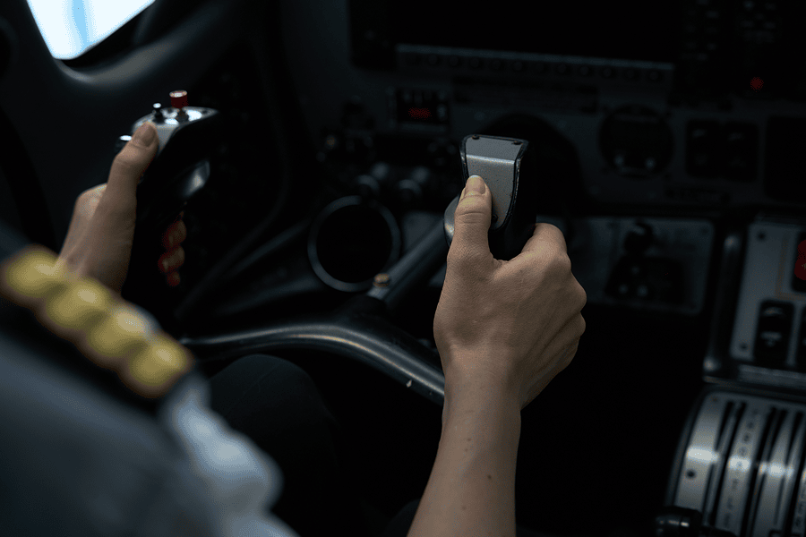 Pilot's hands on cockpit controls.