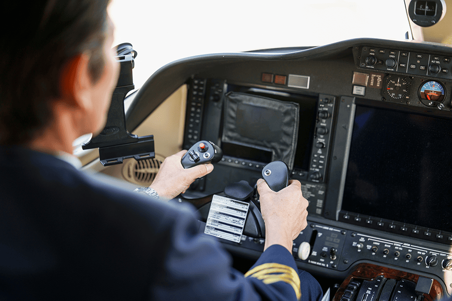 Pilot operating aircraft controls in cockpit.