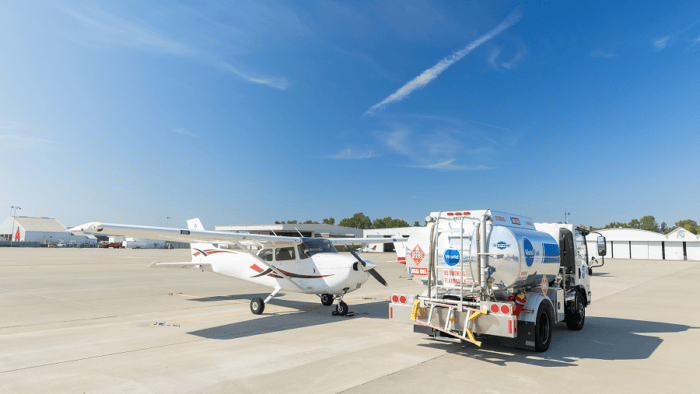 Fuel truck servicing small aircraft on tarmac.