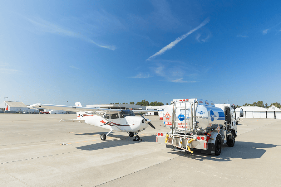 Fuel truck servicing small aircraft on tarmac.