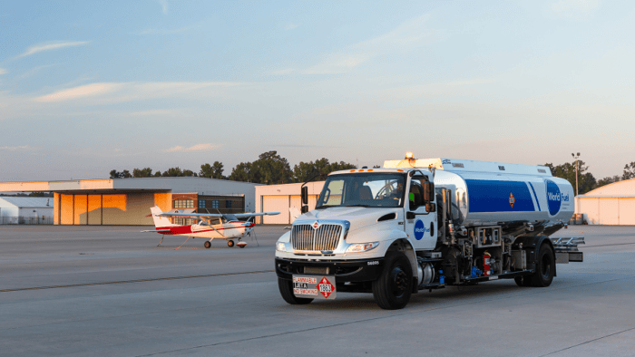 Fuel truck servicing aircraft at airport.