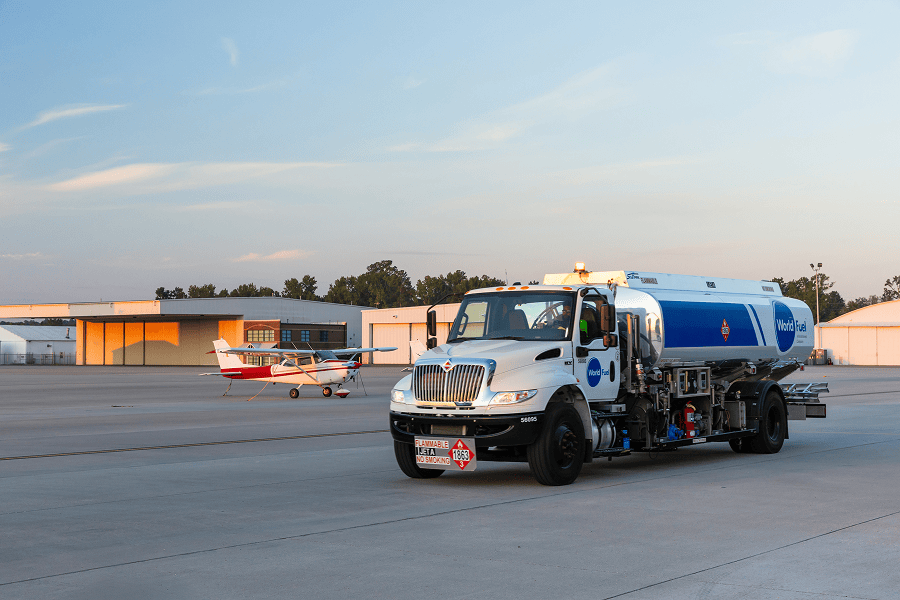 Fuel truck servicing aircraft at airport.