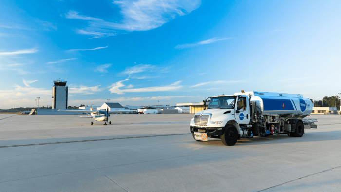 Fuel truck on tarmac with aircraft.