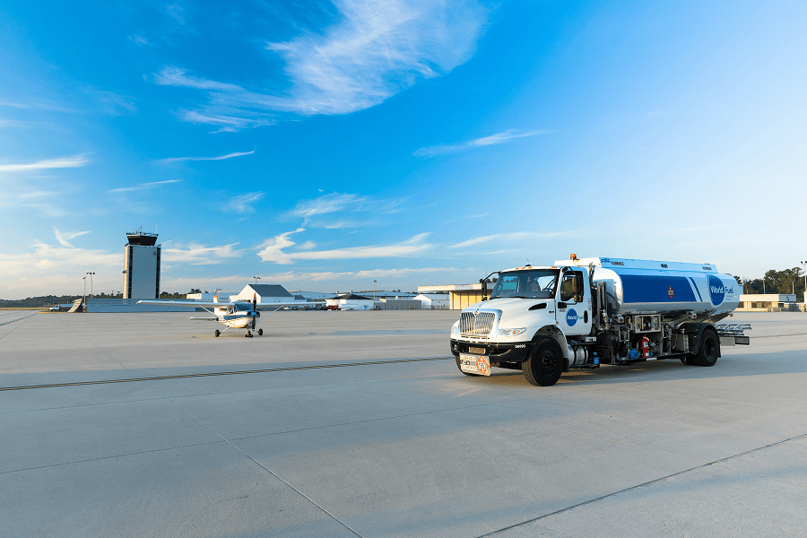 Fuel truck on tarmac with aircraft.