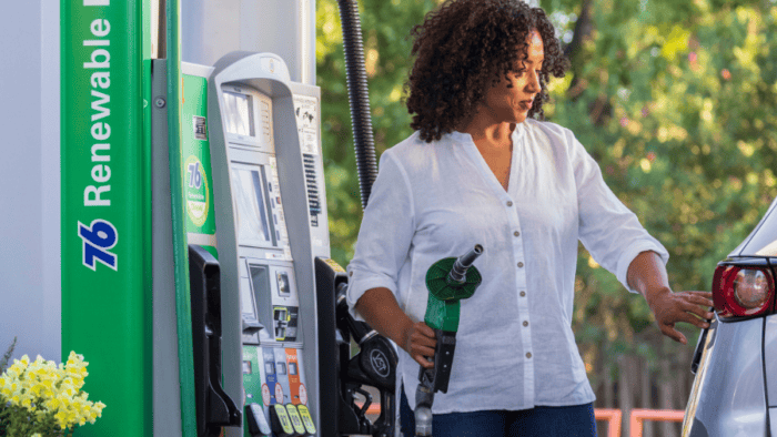 Woman refuelling car at pump.