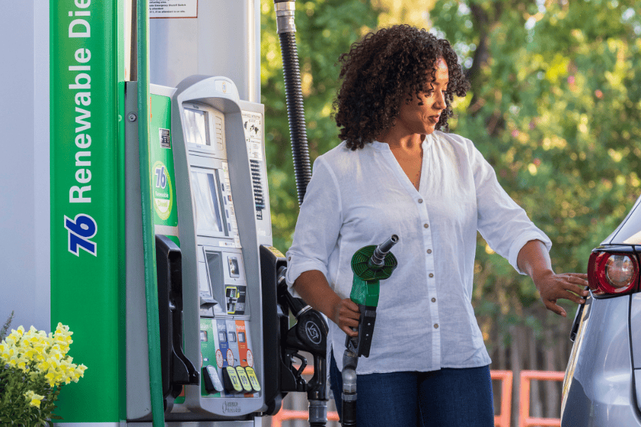 Woman refuelling car at pump.