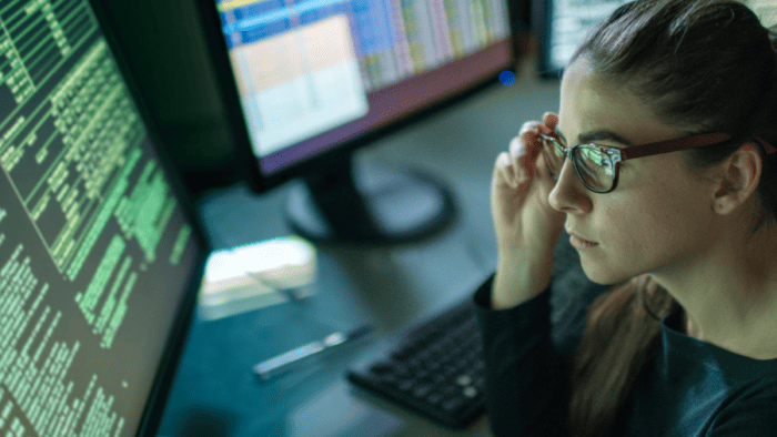 Woman analysing data on computer screens.