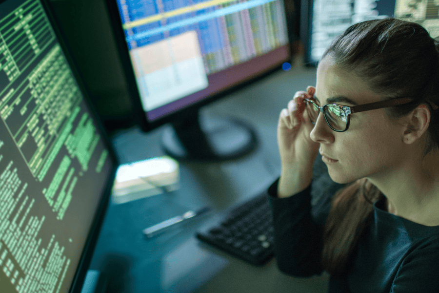 Woman analysing data on computer screens.