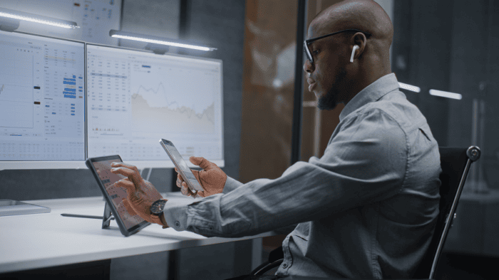 man sitting at desk with monitors and ipads