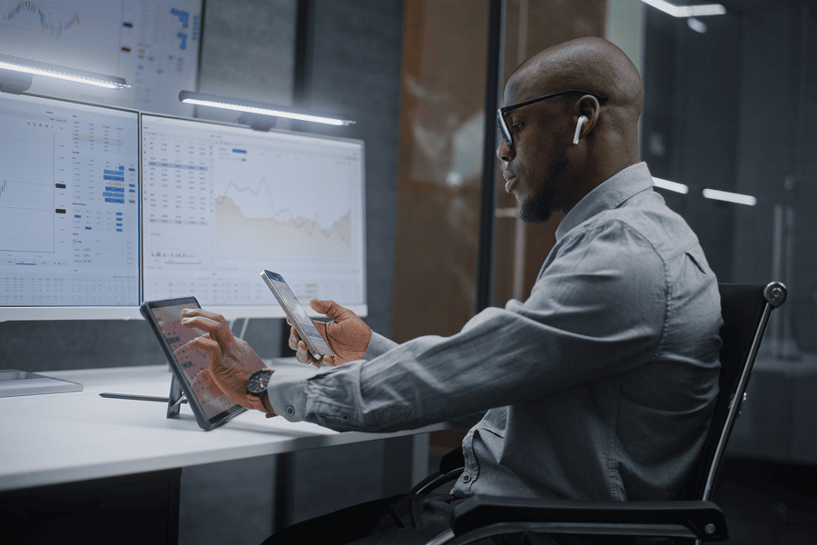 man sitting at desk with monitors and ipads