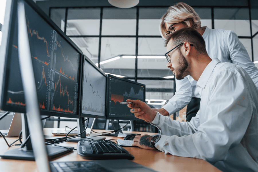 two office workers look at desktop computers
