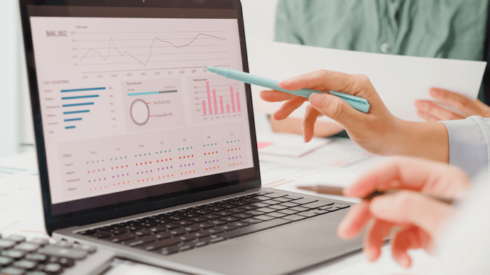 hand pointing to laptop screen witch charts