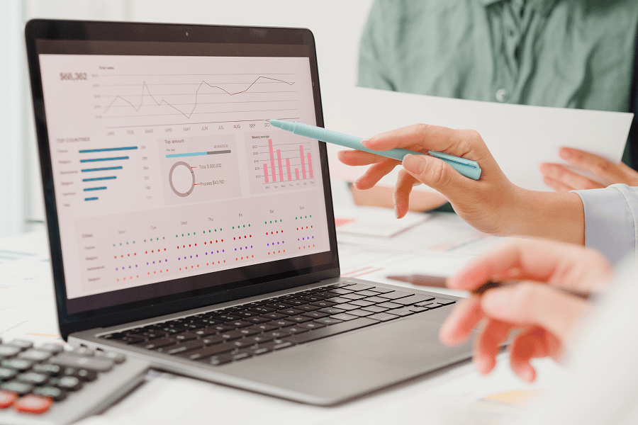 hand pointing to laptop screen witch charts