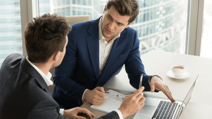 two men sitting in desk speaking