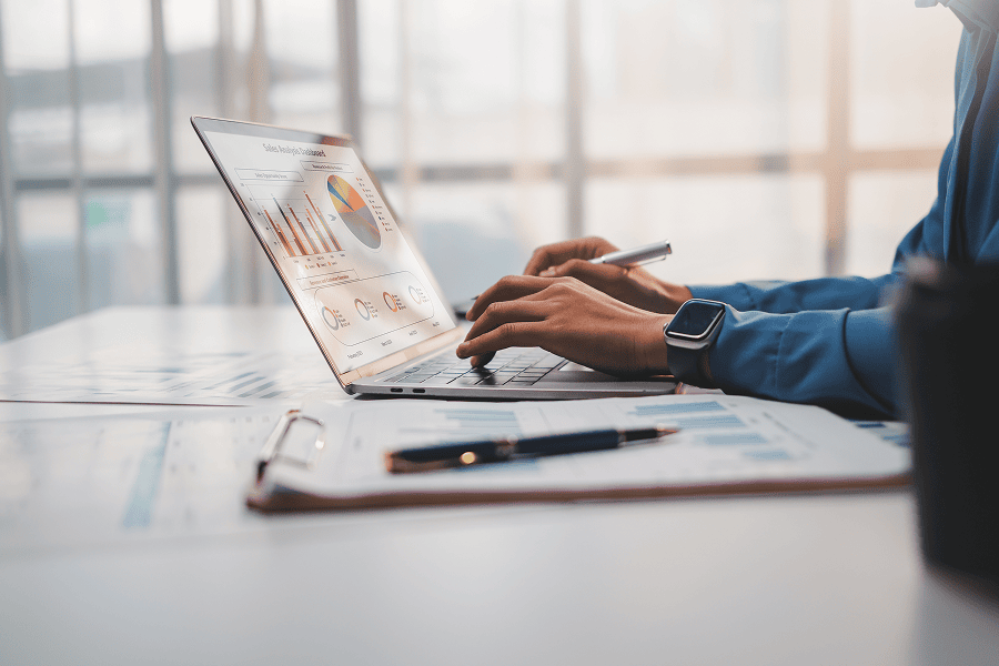 hands on a laptop while viewing a chart on screen