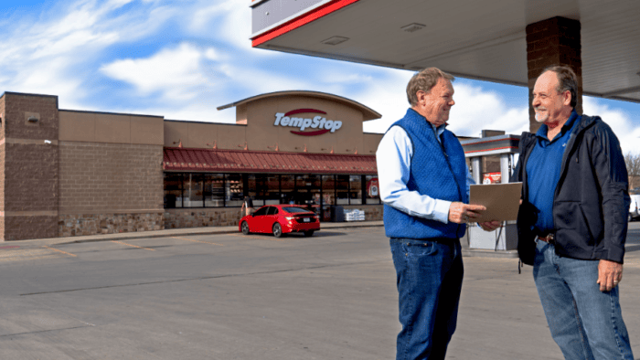 two men speaking in front of a Temp Stop