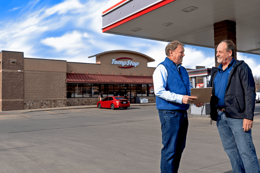 two men speaking in front of a Temp Stop