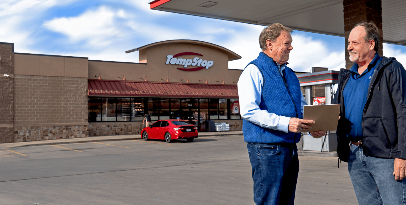 two men speaking in front of a Temp Stop
