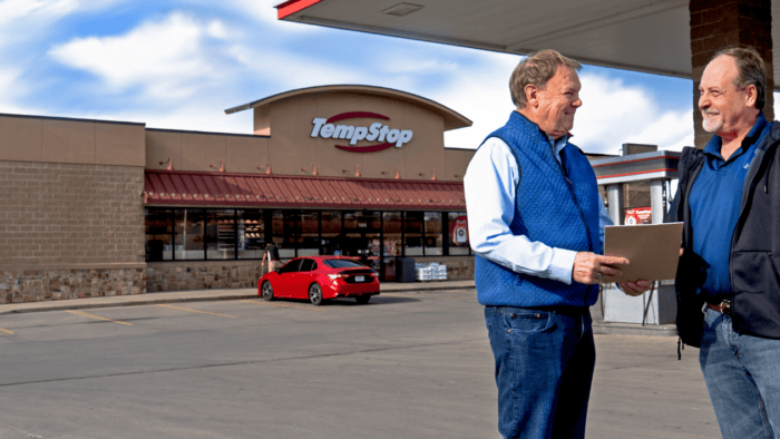 two men speaking in front of a Temp Stop