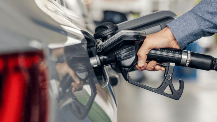 Hand with a nozzle fueling a car