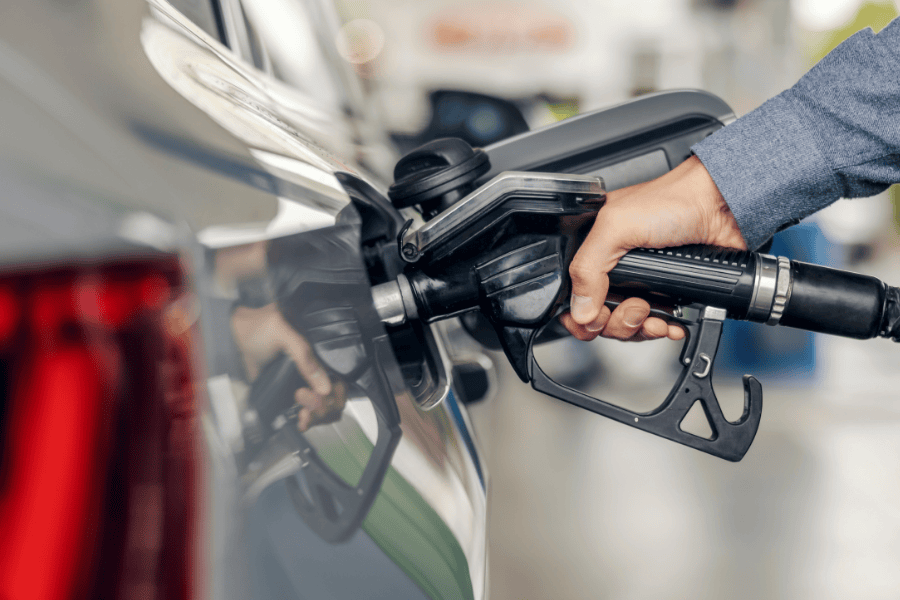 Hand with a nozzle fueling a car