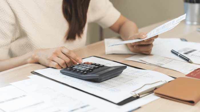 woman with hand on desk top calculator