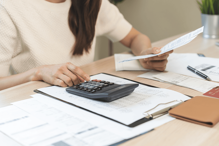woman with hand on desk top calculator