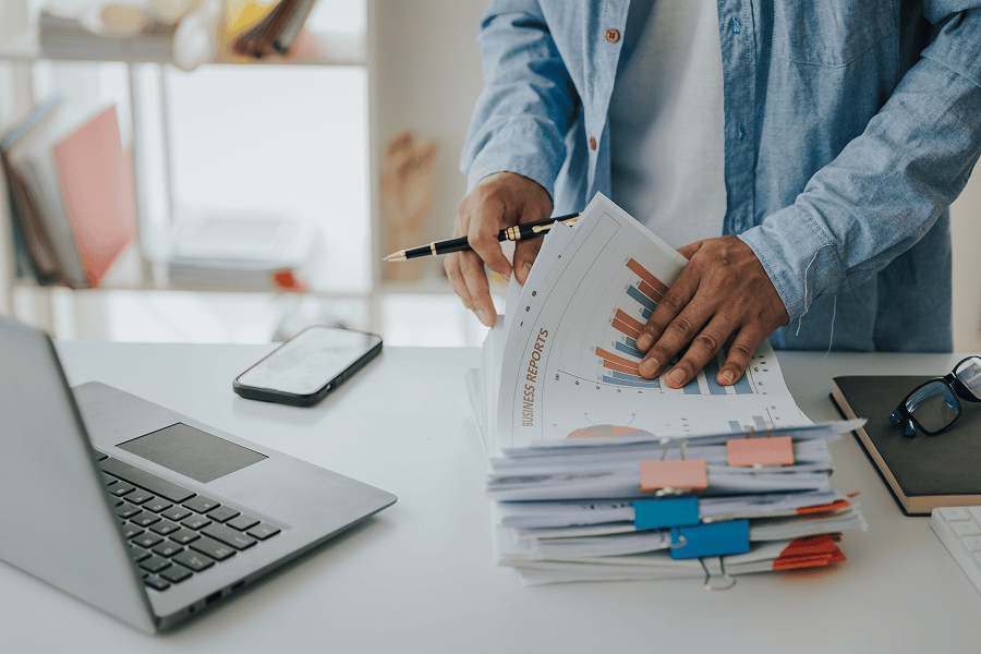 Man organising documents with laptop.