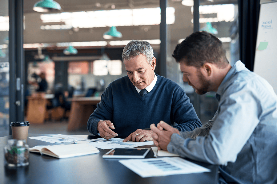 Two men discussing documents in office.