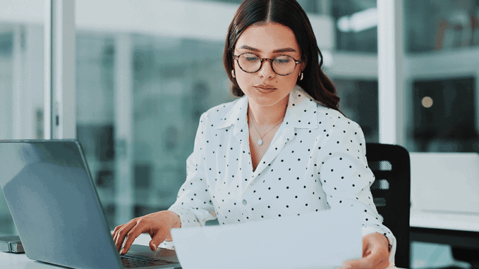 Businesswoman reviewing finance report at desk.