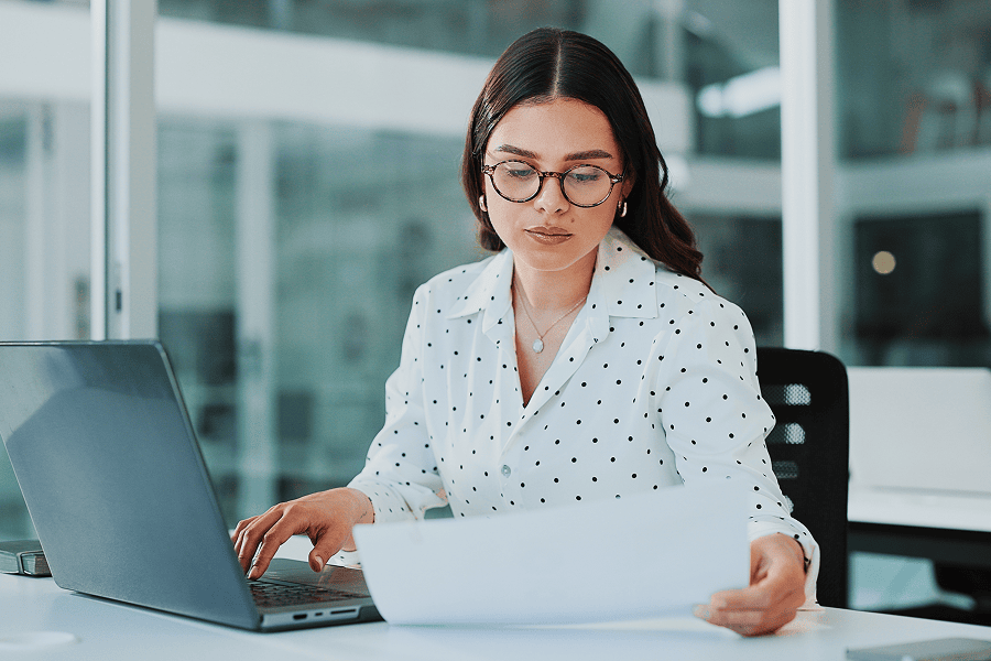 Businesswoman reviewing finance report at desk.