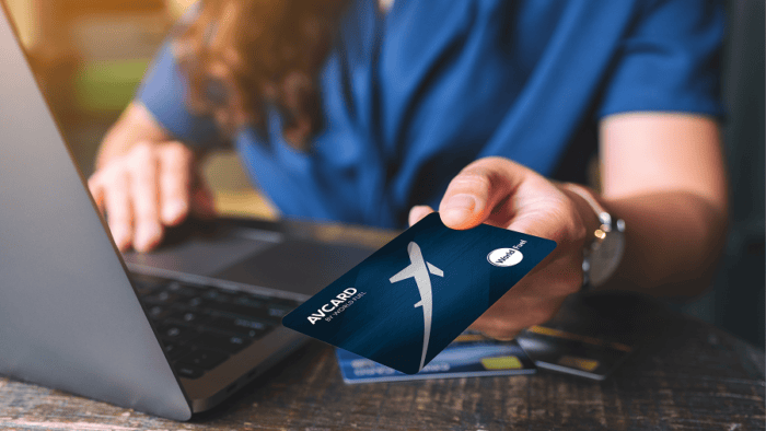 Person holding card near laptop.