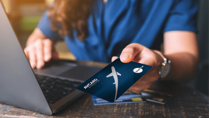 Person holding card near laptop.