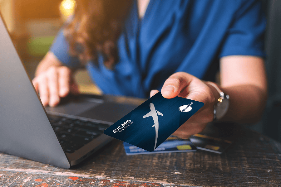 Person holding card near laptop.