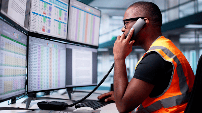 Man in vest using multiple monitors