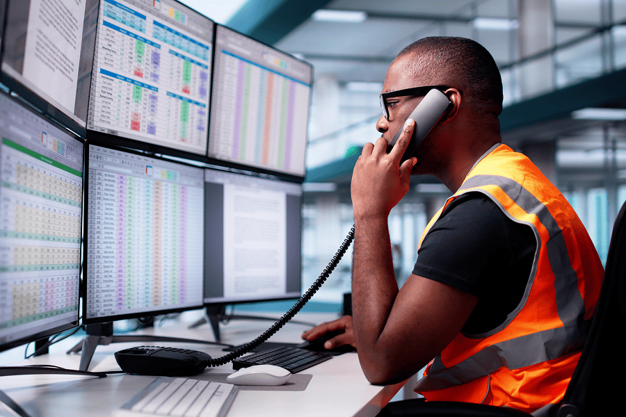 Man in vest using multiple monitors