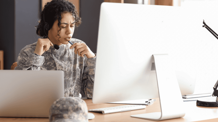 A female soldier wearing a headset working on a computer