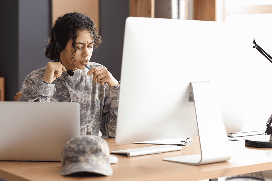 A female soldier wearing a headset working on a computer