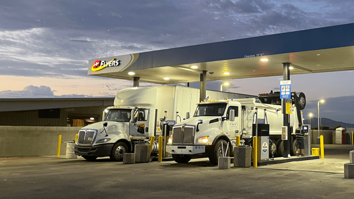 Two commercial transport trucks refueling at a Flyers cardlock fuel station at night