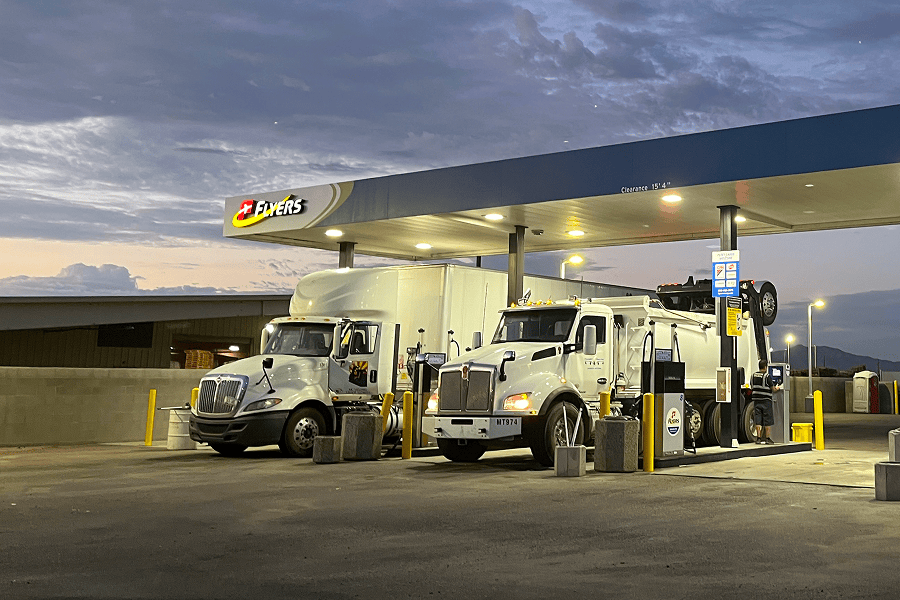 Two commercial transport trucks refueling at a Flyers cardlock fuel station at night