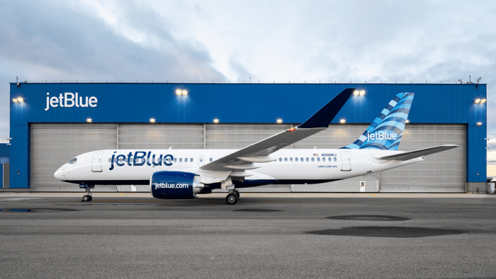 JetBlue aircraft parked on the airport apron in front of a JetBlue facility building.