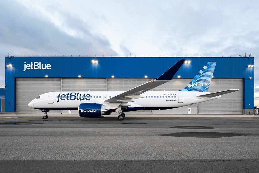 JetBlue aircraft parked on the airport apron in front of a JetBlue facility building.