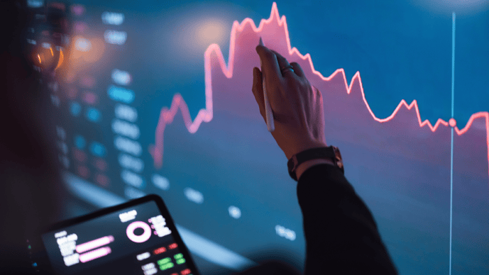 Person analyzing a digital dashboard with charts and trend lines displayed on a large interactive screen.