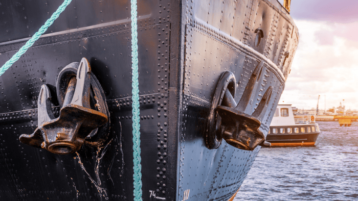 Close-up view of a ship’s bow with two anchors secured to the hull while docked near a harbor.
