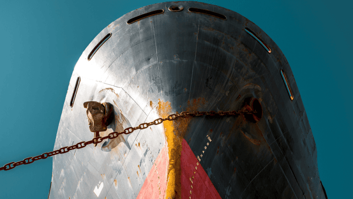 Close-up view of the bow of a large cargo ship with anchor chains extending across the vessel’s hull.