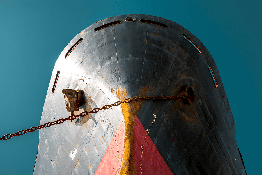 Close-up view of the bow of a large cargo ship with anchor chains extending across the vessel’s hull.